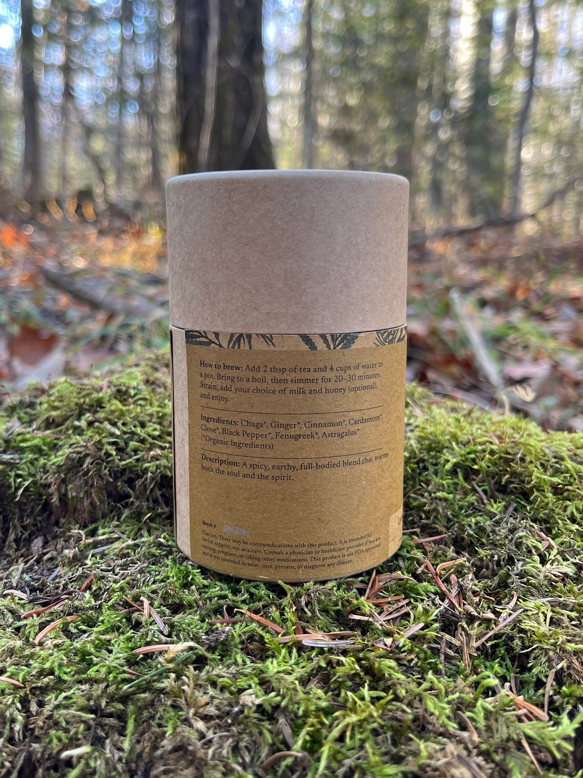Cylindrical container with label on a mossy tree trunk in a forest setting