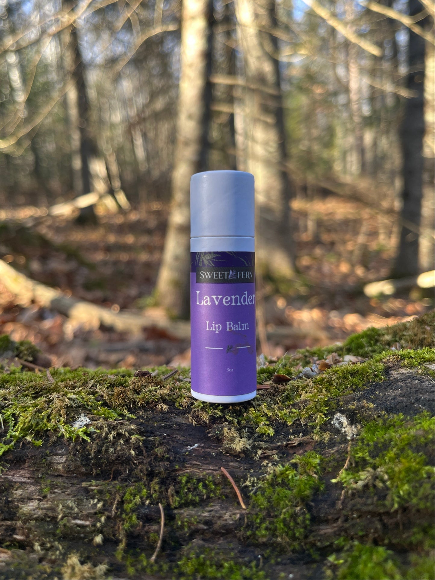 Lavender lip balm on a tree trunk with a forest background
