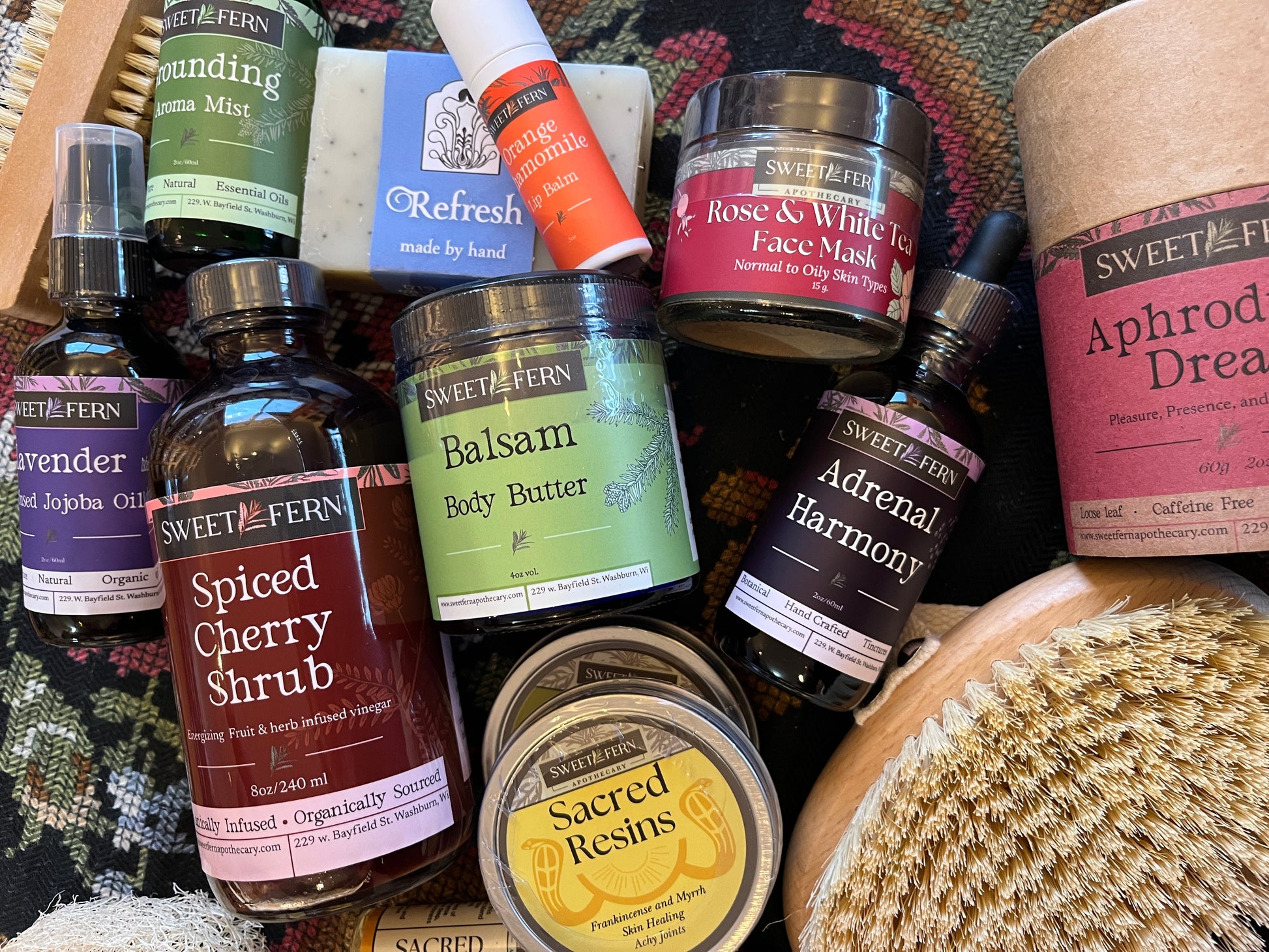 Collection of Sweet Fern skincare and wellness products on a textured surface